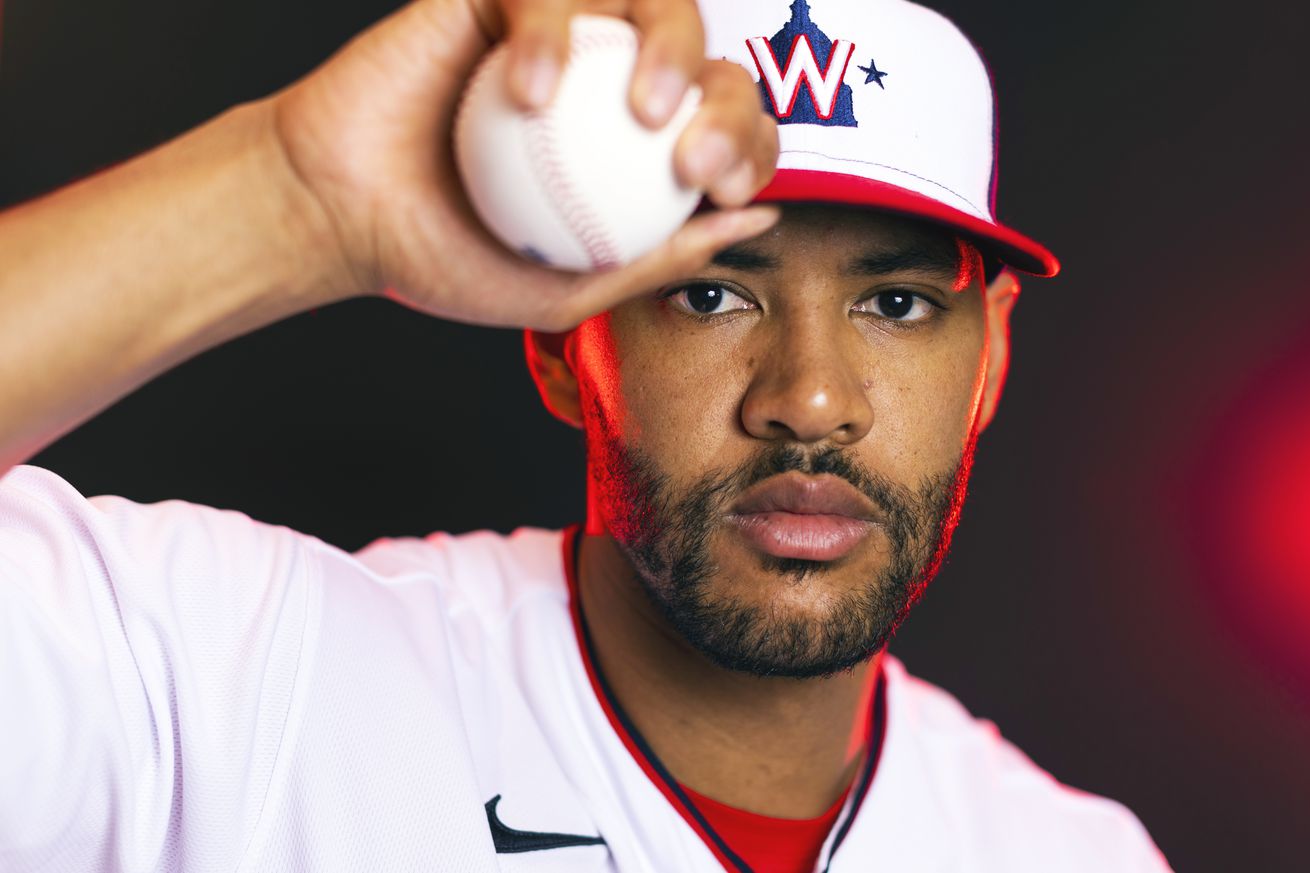 Joe Ross posing in a Nationals jersey, holding a baseball and his hat bill in his right hand