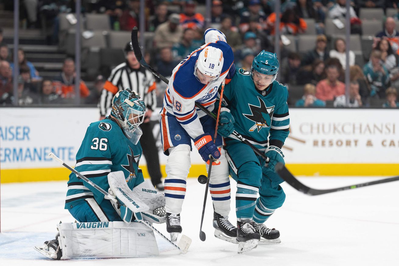 Jan 13, 2023; San Jose, California, USA; Edmonton Oilers left wing Zach Hyman (18) attempts to jump out of the way of the puck during the first period against San Jose Sharks goaltender Kaapo Kahkonen (36) and defenseman Matt Benning (5) at SAP Center at San Jose.