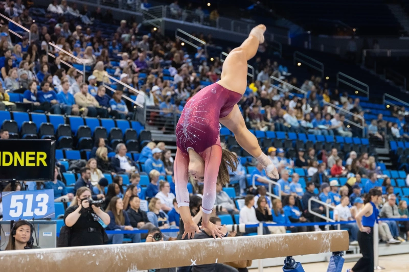 A women doing a flip on a beam