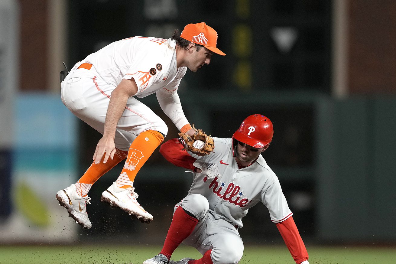 Casey Schmitt jumping in the air to avoid a slide at second base by Kody Clemens