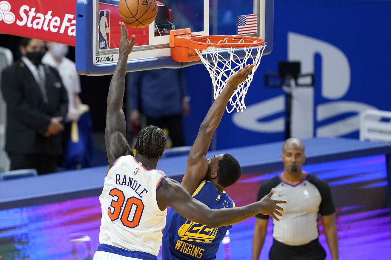 Julius Randle shooting a layup as Andrew Wiggins tries to block it. 