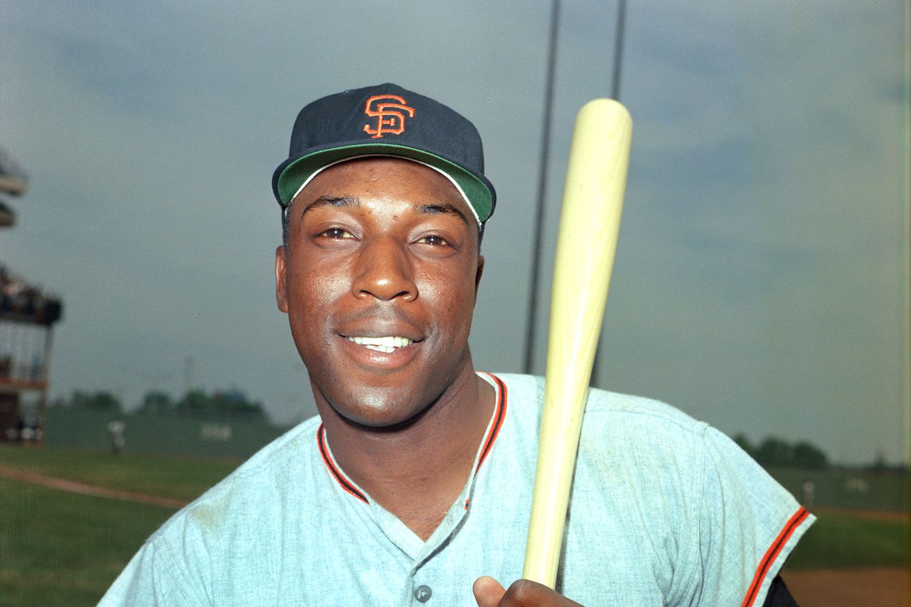 Willie McCovey smiling with a bat on his shoulder.