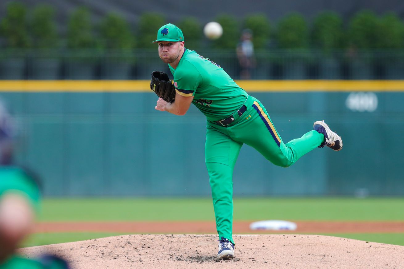 View from behind home plate as John Michael Bertrand throws a pitch in a Notre Dame jersey.