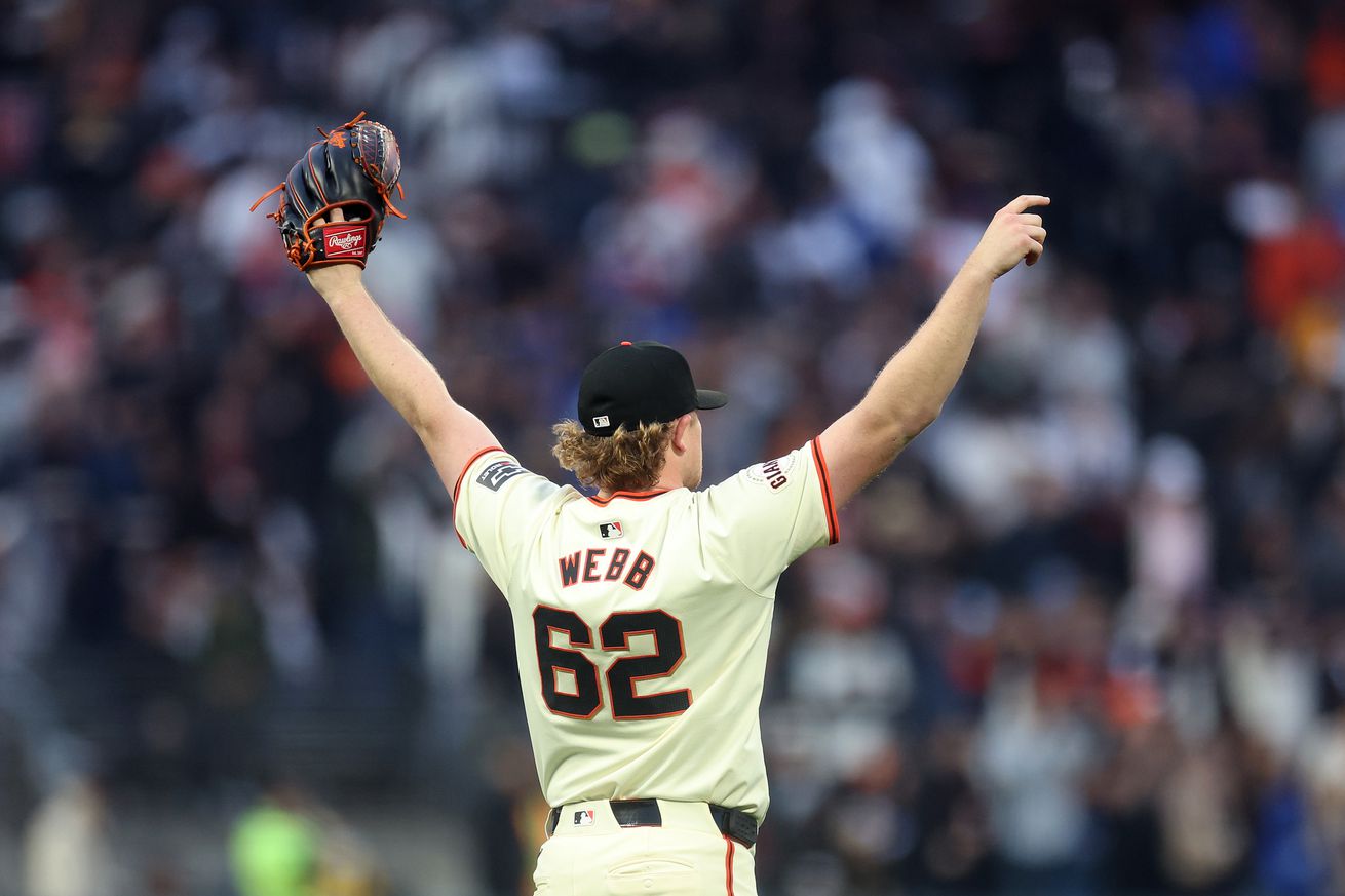 View from behind of Logan Webb raising his arms in celebration.