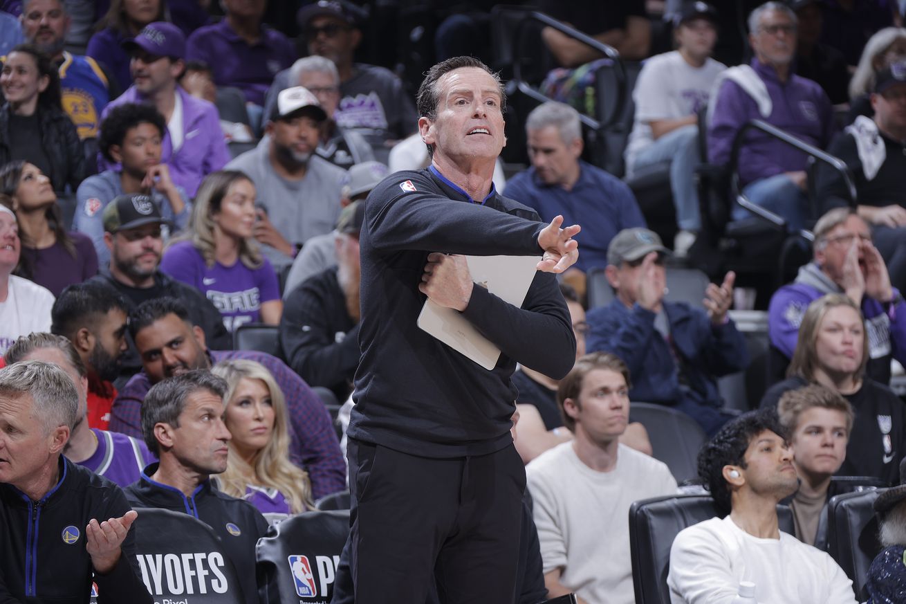 Kenny Atkinson holding a clipboard, directing players. 