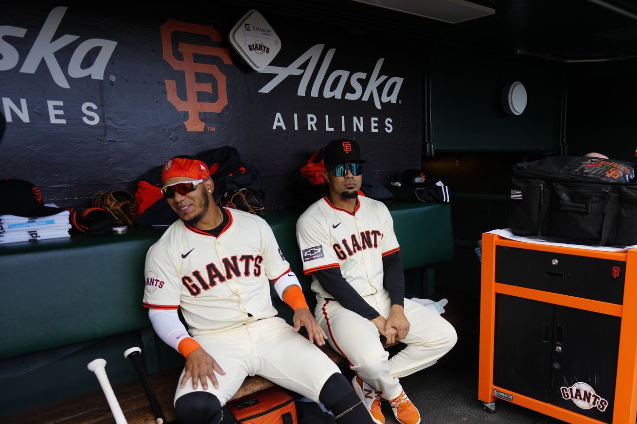 Thairo Estrada and LaMonte Wade Jr. sitting next to each other in the dugout. 