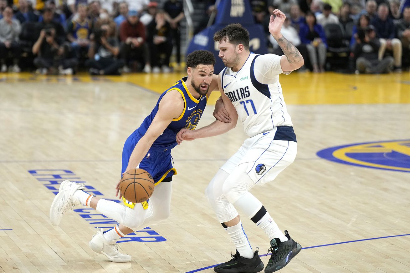 Klay Thompson dribbling with his right hand by Luka Dončić. 