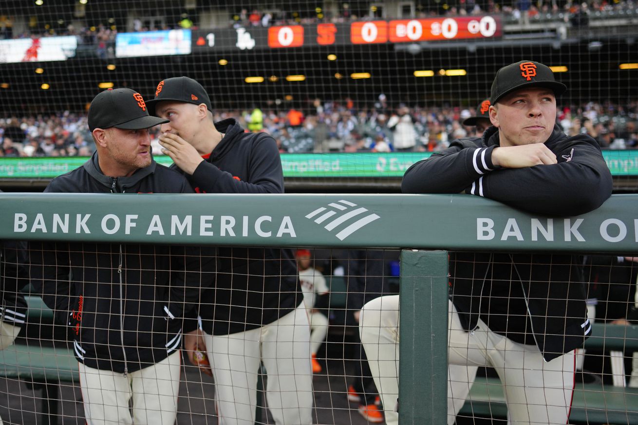 Blake Snell whispering in Alex Cobb’s ear in the dugout, with Kyle Harrison leaning over the rail nearby. 