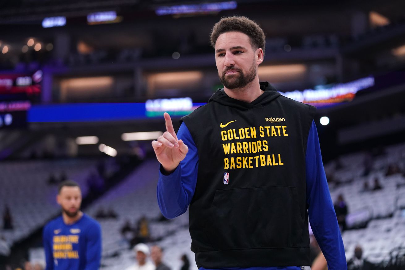 Klay Thompson smiling in warm-ups, while holding a finger up. 