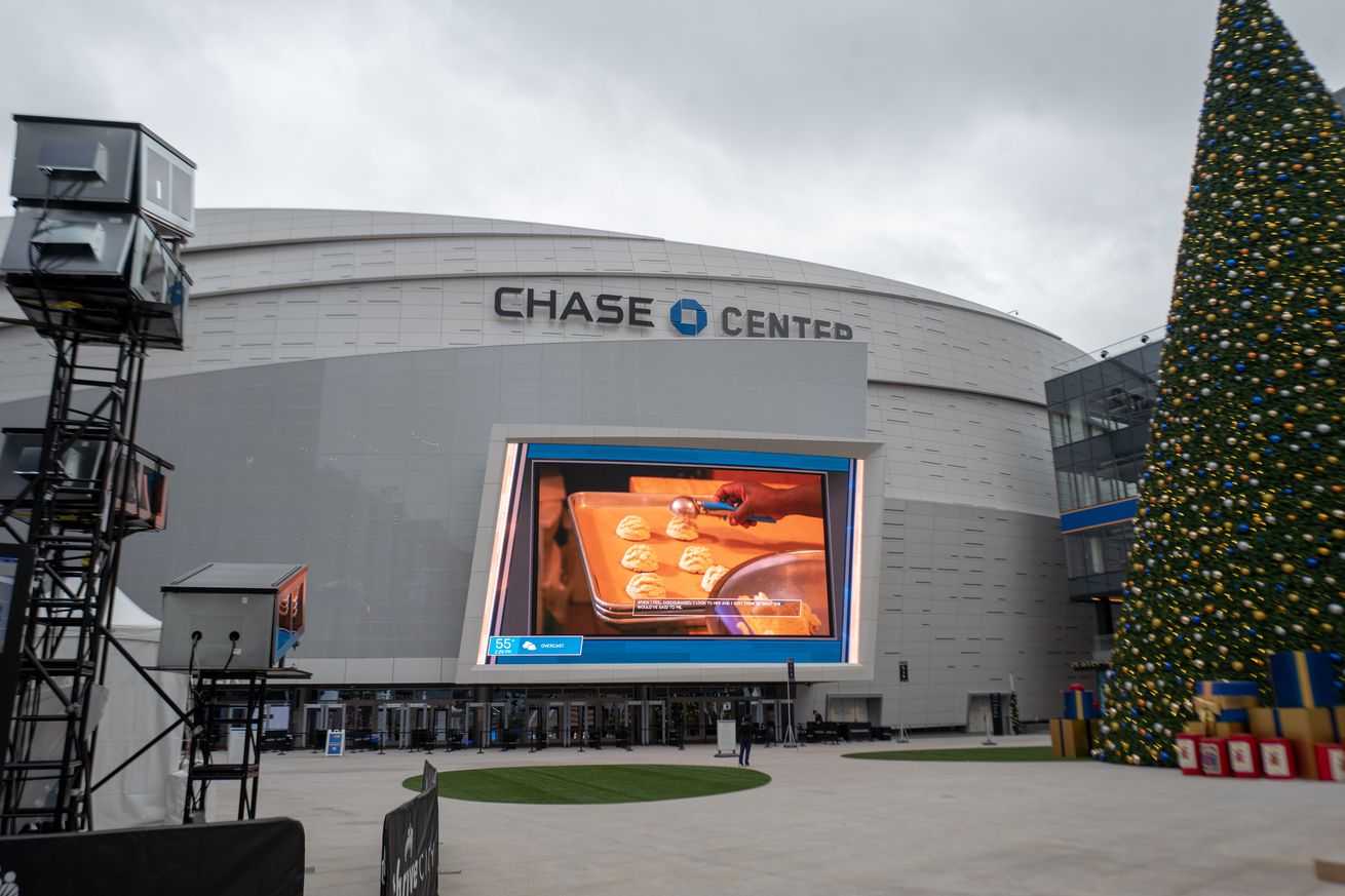 The outside of the Chase Center with the jumbotron, next to a Christmas tree. 