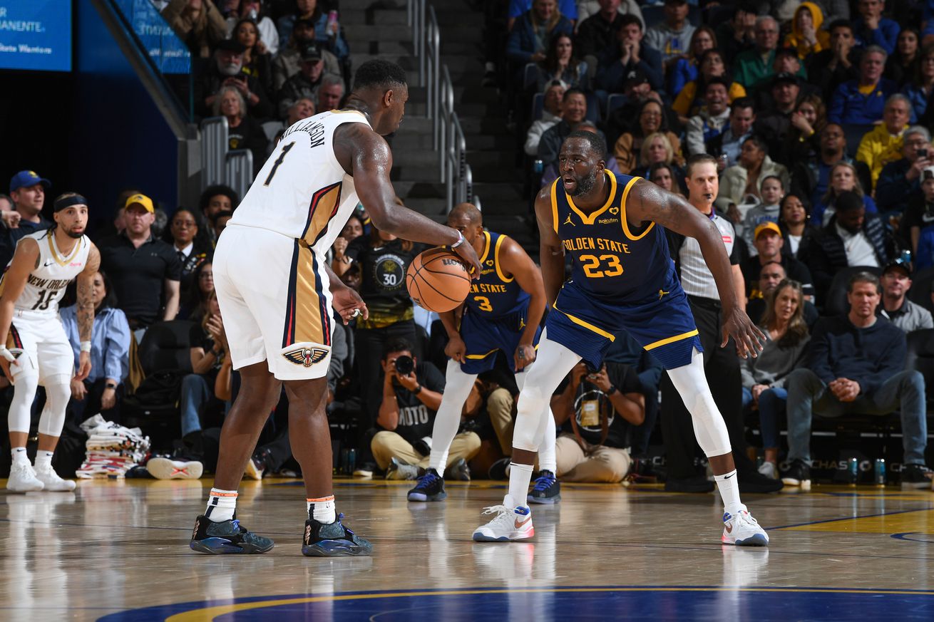 Draymond Green in a defensive stance, guarding Zion Williamson. 