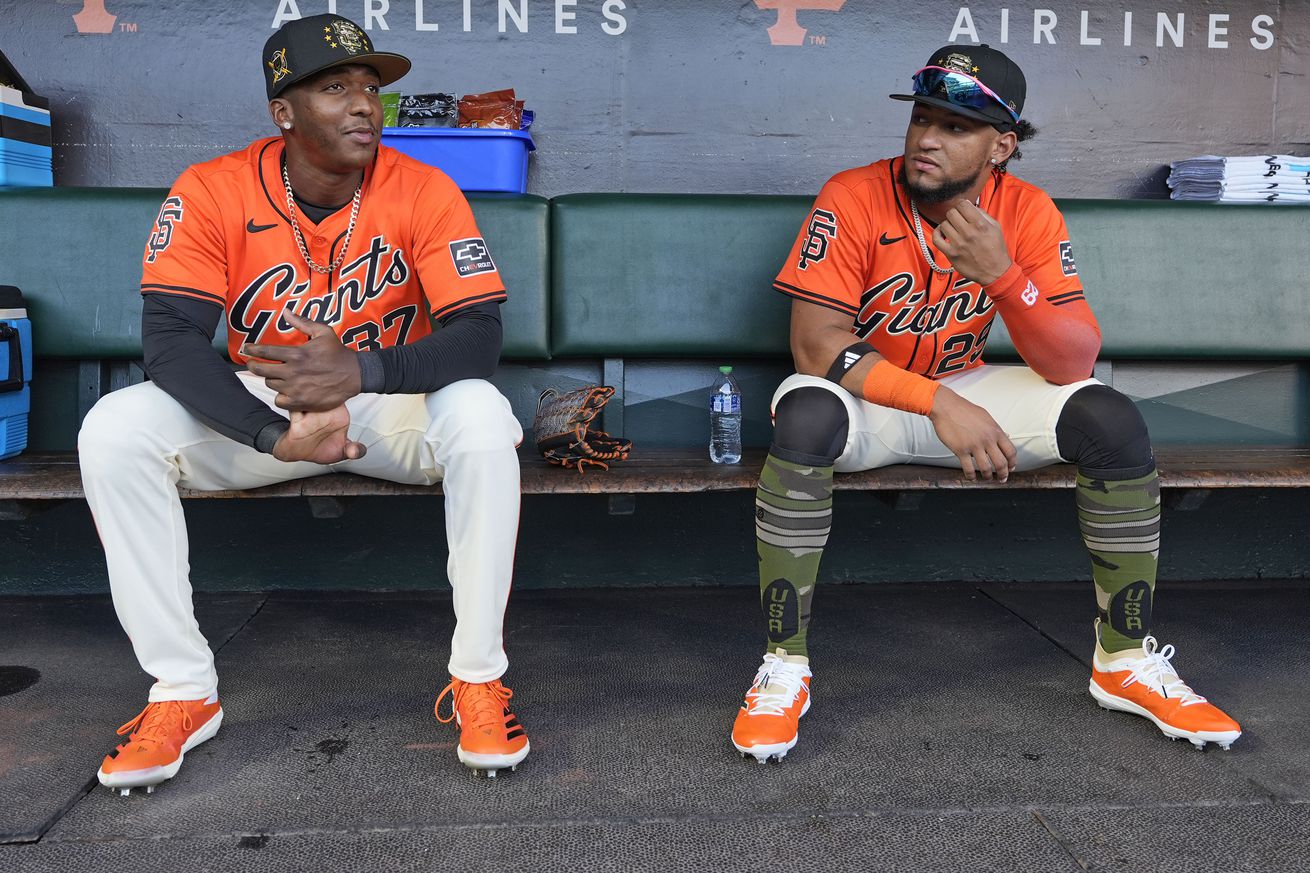 Marco Luciano sitting next to Luis Matos in the Giants dugout. 