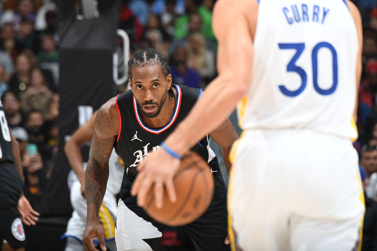 Kawhi Leonard waiting to guard Steph Curry as Curry dribbles up the court. 