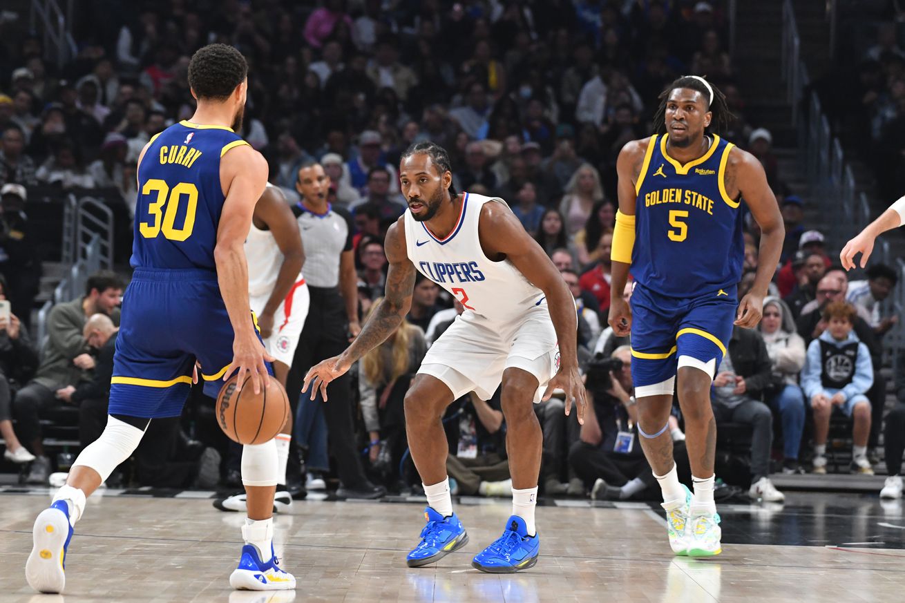 Kawhi Leonard waiting to defend Steph Curry as Curry dribbles up the court, with Kevon Looney waiting behind to set a screen