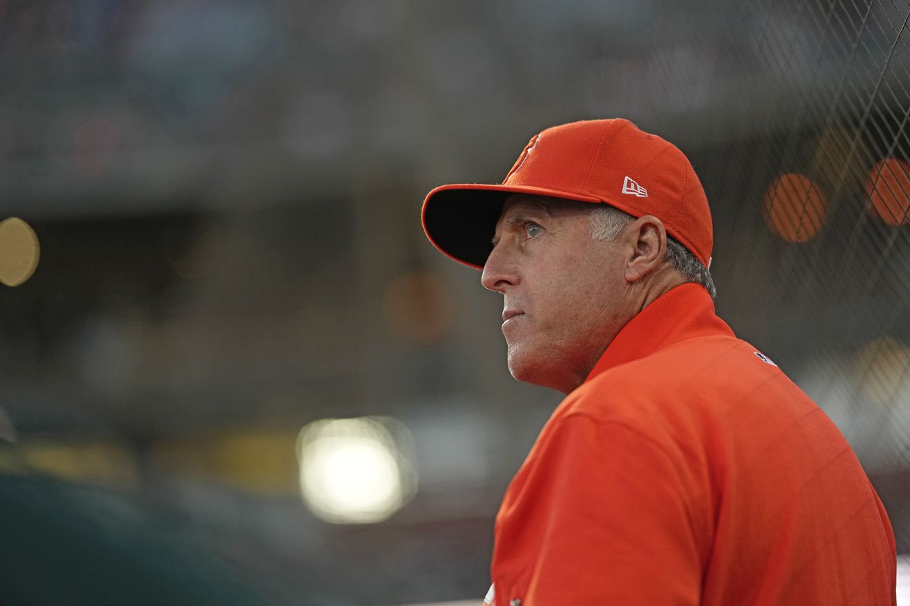 Bryan Price, wearing orange, looking over his shoulder. 