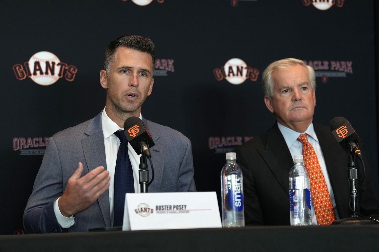 Buster Posey talking at a press conference next to Greg Johnson. 