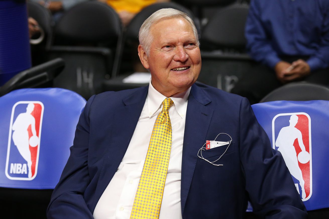 Jerry West smiling while sitting courtside. 