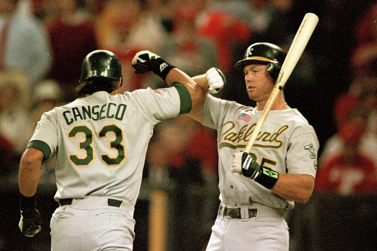 Cincinnati, OH Ocotber 17, 1990: Jose Canseco, left, and Oakland Athletics teammate Mark McGwire, exchange their “Bash Brothers” salute after Canseco homered during game two of the 1990 World Series against the Cincinnati Reds at Riverpoint Stadium. (Jose