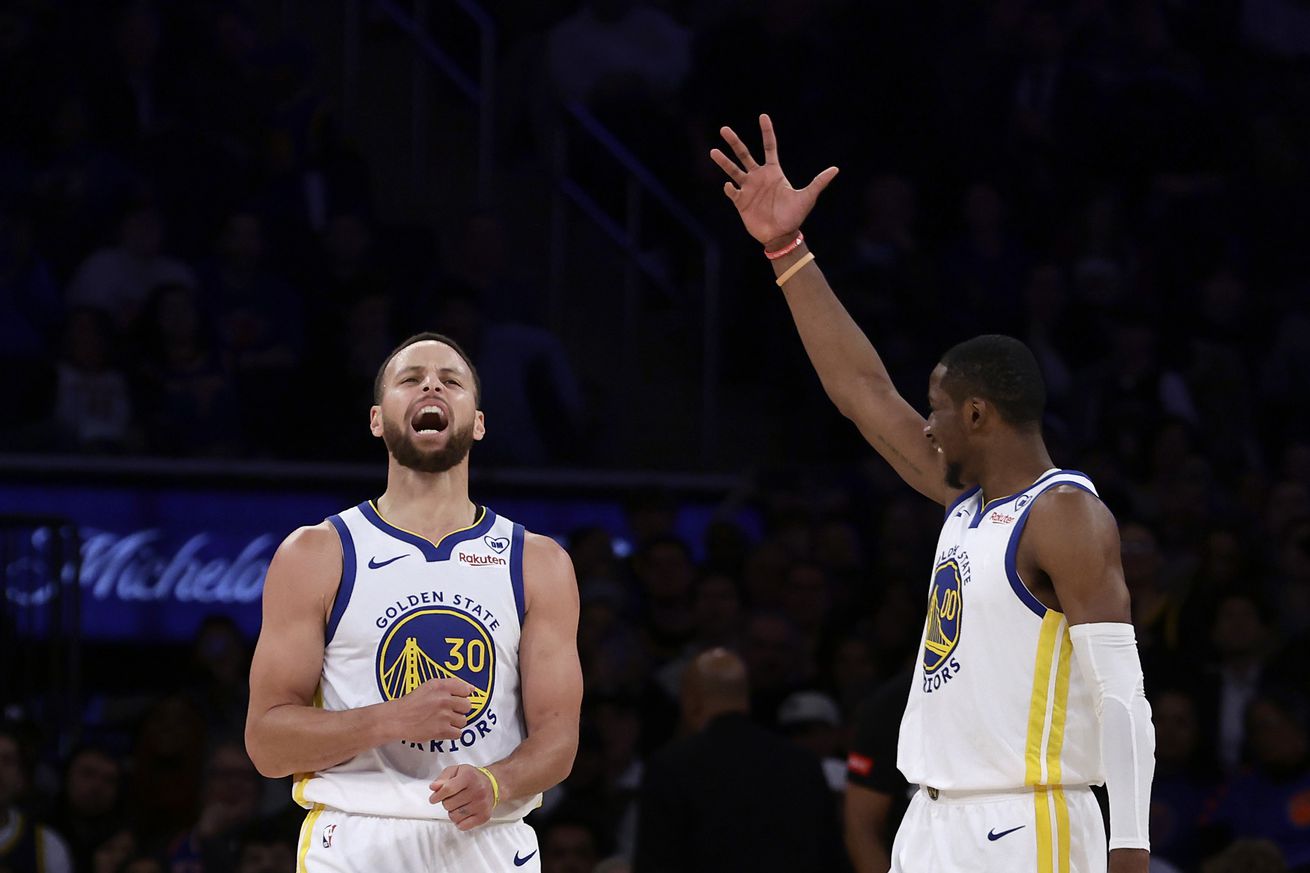 Steph Curry screaming in excitement while Jonathan Kuminga raises his hand in celebration.