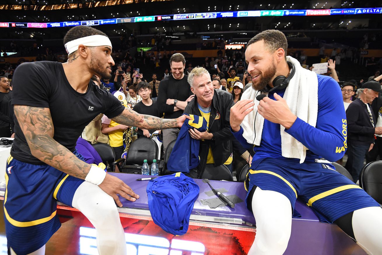 Steph Curry sitting on the broadcast table next to Gary Payton II, with Will Ferrell behind them.