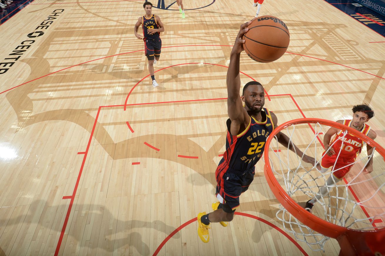 View from above the hoop as Andrew Wiggins flies for a dunk with a Hawks defender behind him. 