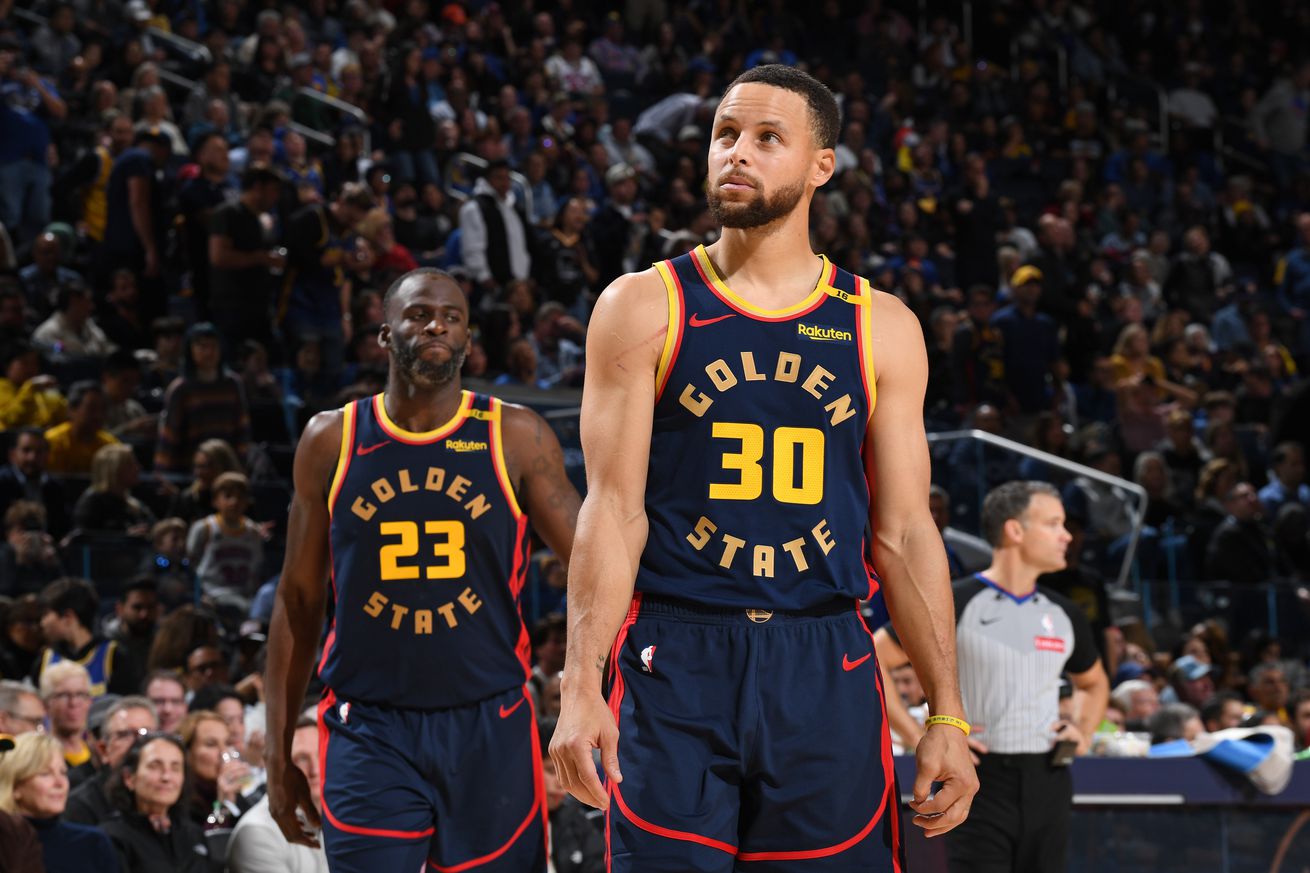 Steph Curry standing in a jersey with Draymond Green behind him. 