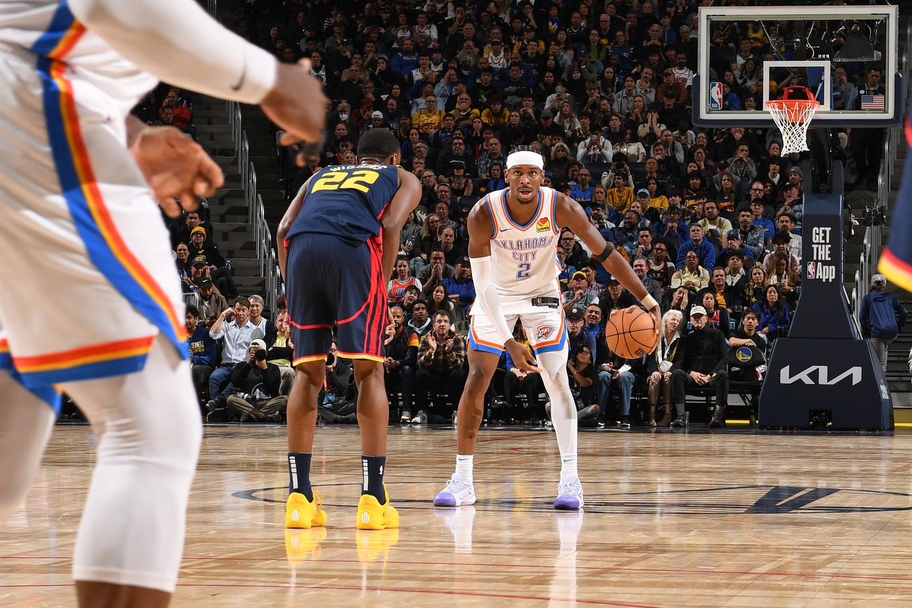 Shai Gilgeous-Alexander dribbling while Andrew Wiggins defends. 