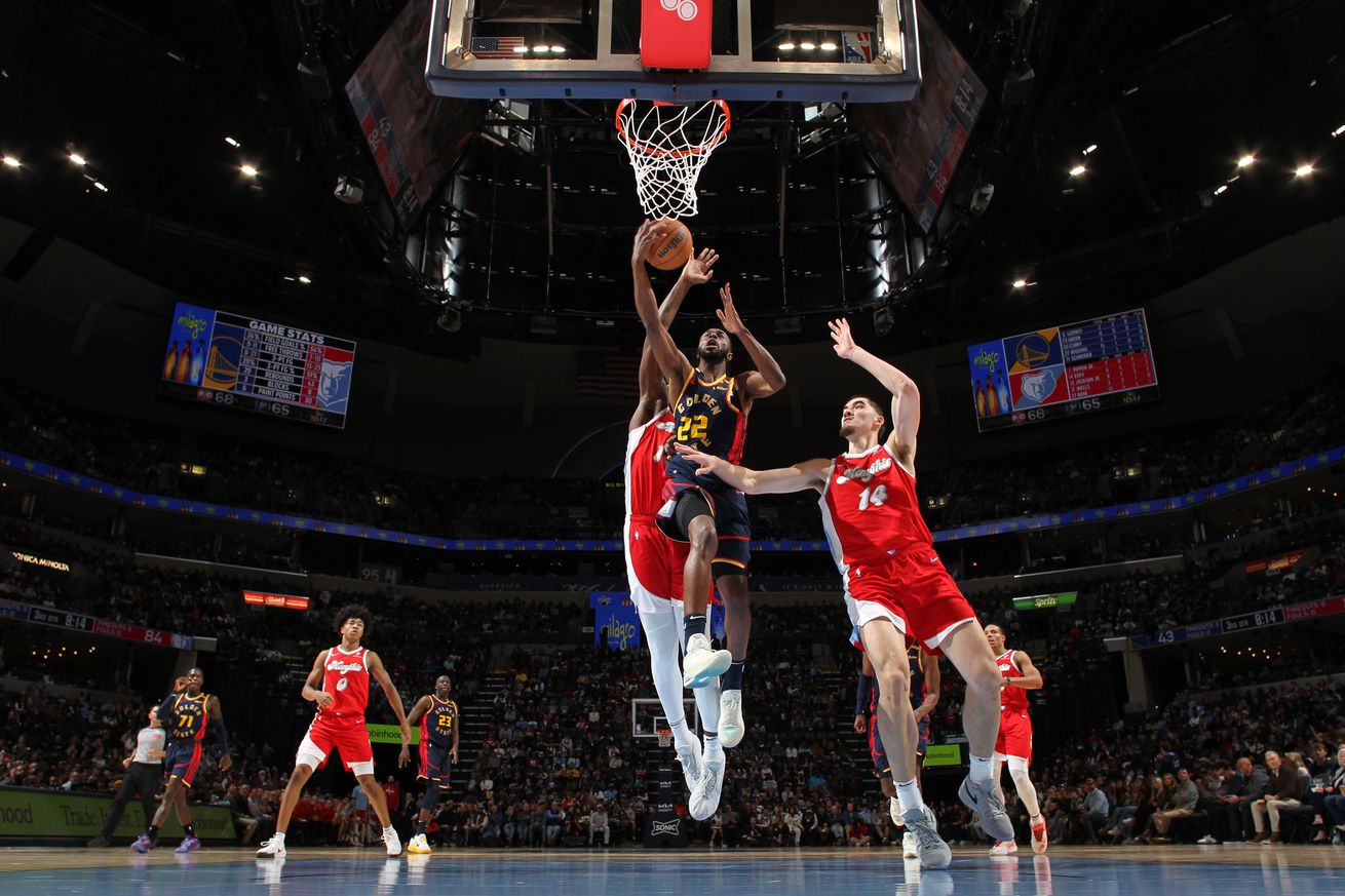 Andrew Wiggins shooting a layup while surrounded by Grizzlies defenders. 