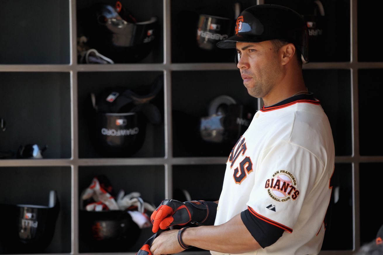 Carlos Beltrán in the dugout wearing a Giants jersey.