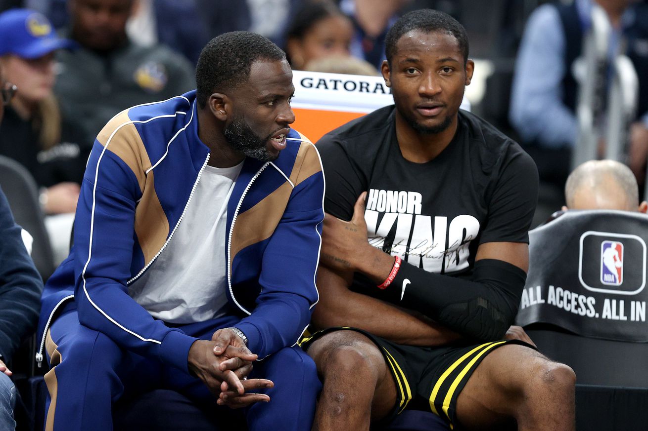 Draymond Green talking with Jonathan Kuminga on the bench. 