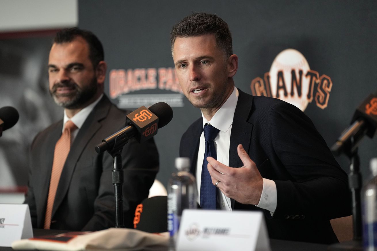 Buster Posey talking at a press conference next to Zack Minasian. 