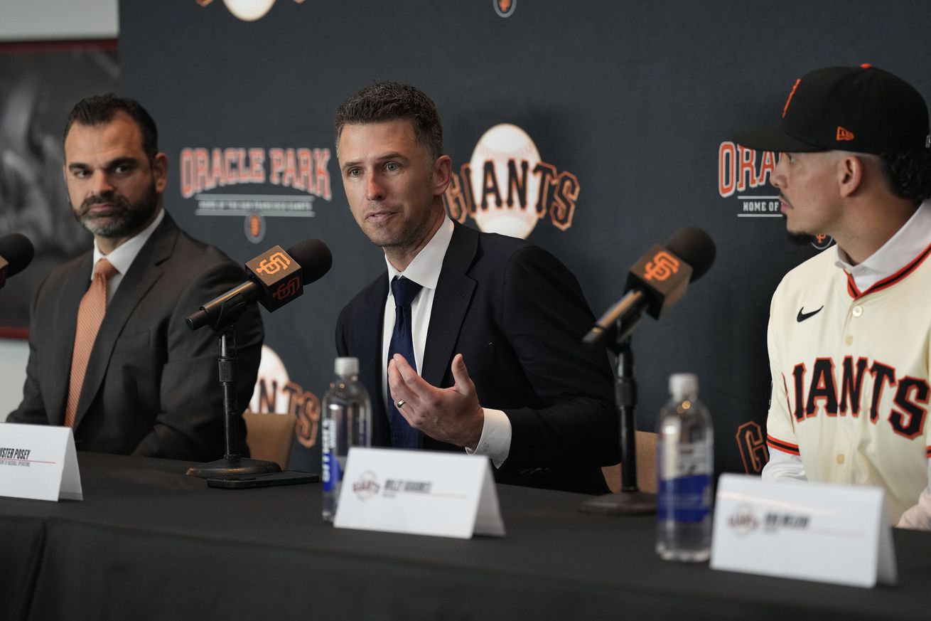 Buster Posey talking while flanked by Zack Minasian and Willy Adames. 