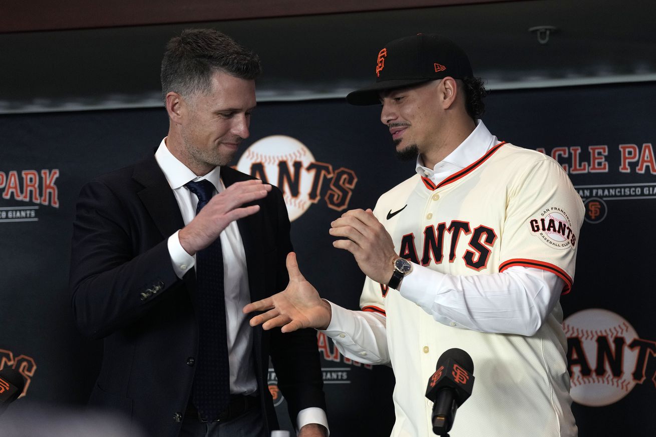 Buster Posey and Willy Adames reaching out to shake hands at a press conference. 