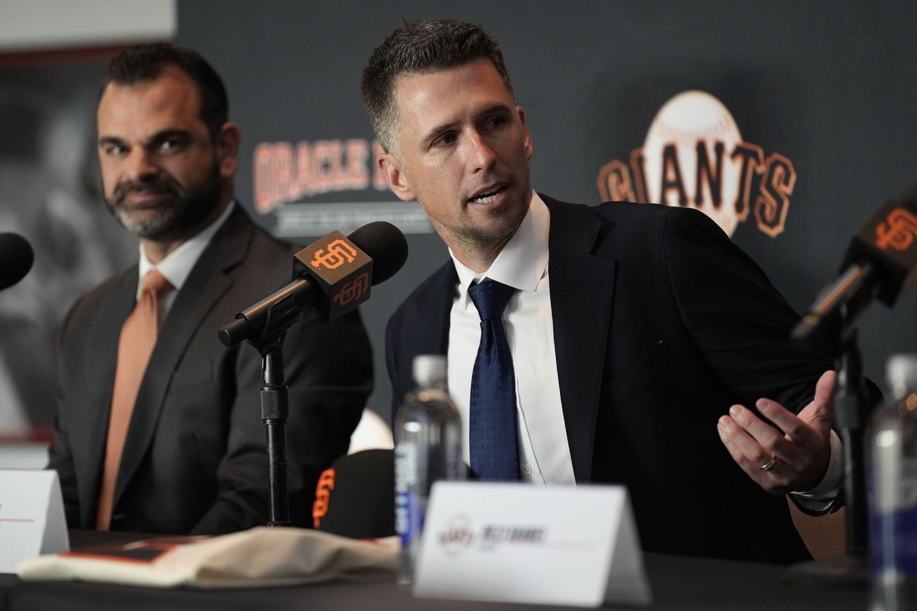 Buster Posey and Zack Minasian talking at a press conference. 