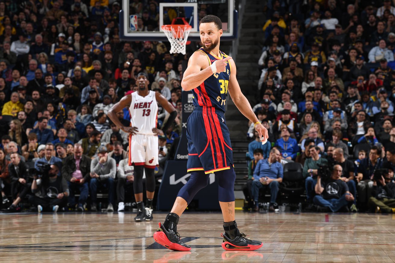 Steph Curry walking down the court with a Heat player in the distance. 