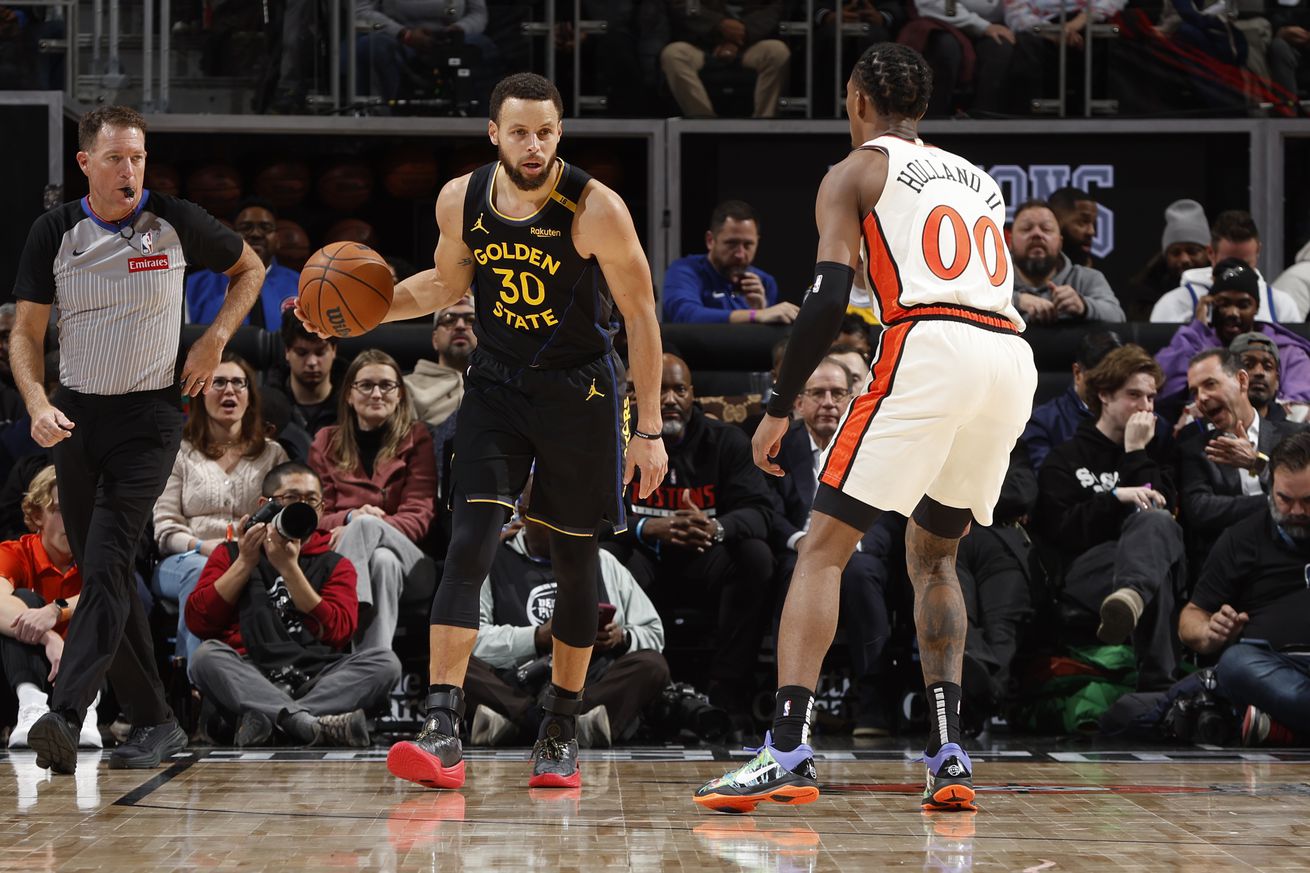 Steph Curry dribbling while defended by Ron Holland III. 