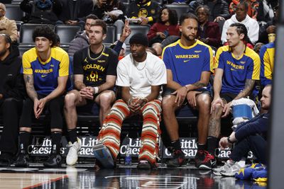 Jonathan Kuminga wearing striped pants on the bench next to his teammates. 