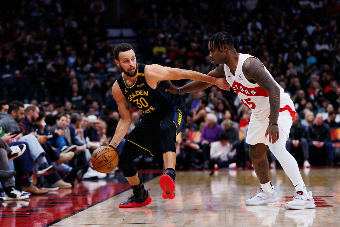 Steph Curry dribbling while defended by Davion Mitchell. 