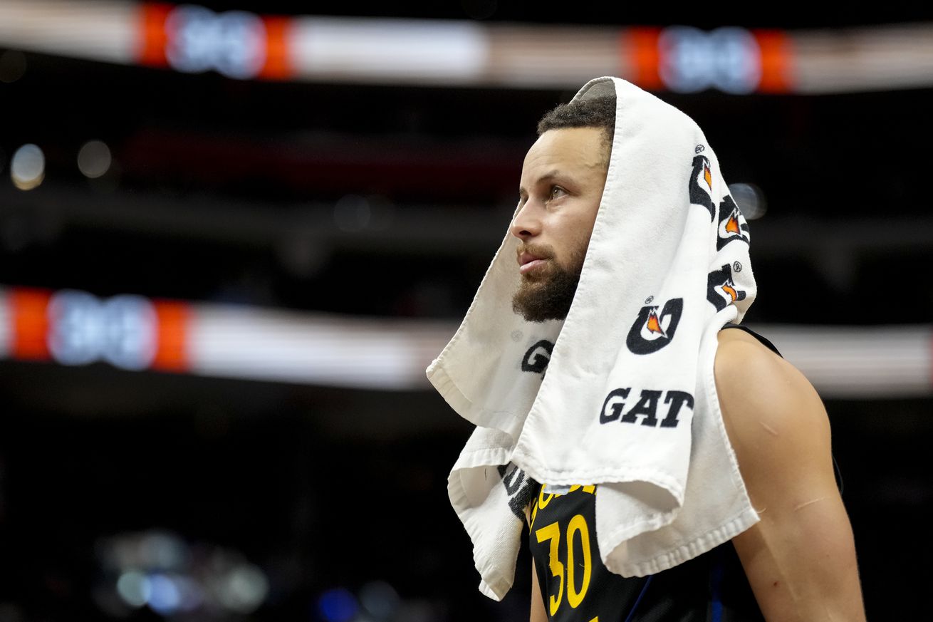 Steph Curry standing with a towel over his head. 