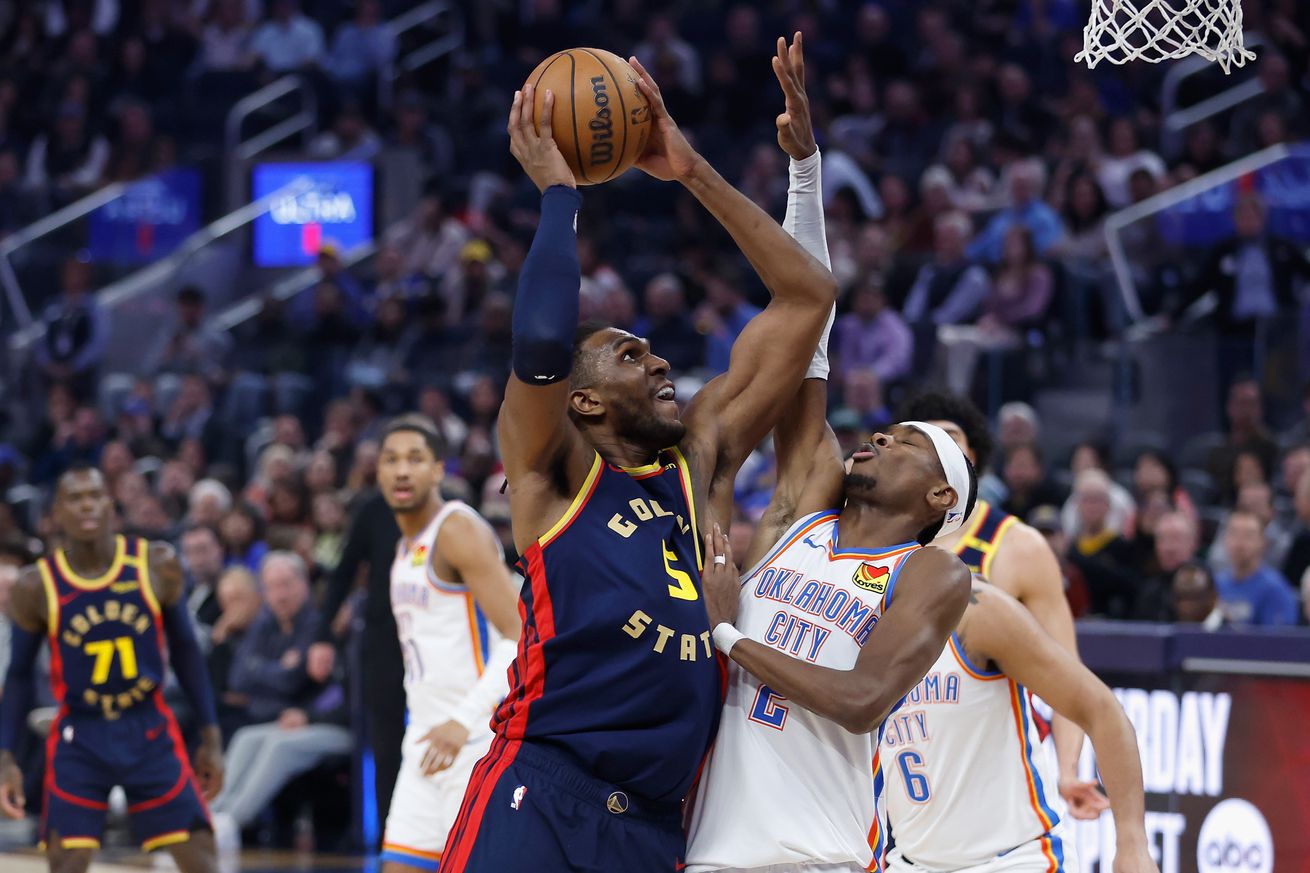 Kevon Looney attempting a layup while defended by Shai Gilgeous-Alexander.