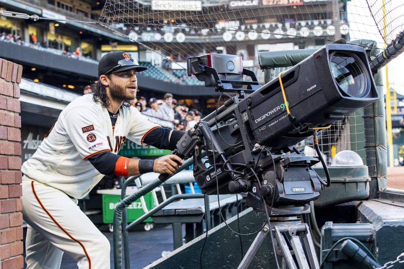 Brandon Crawford in the dugout, operating a game camera. 