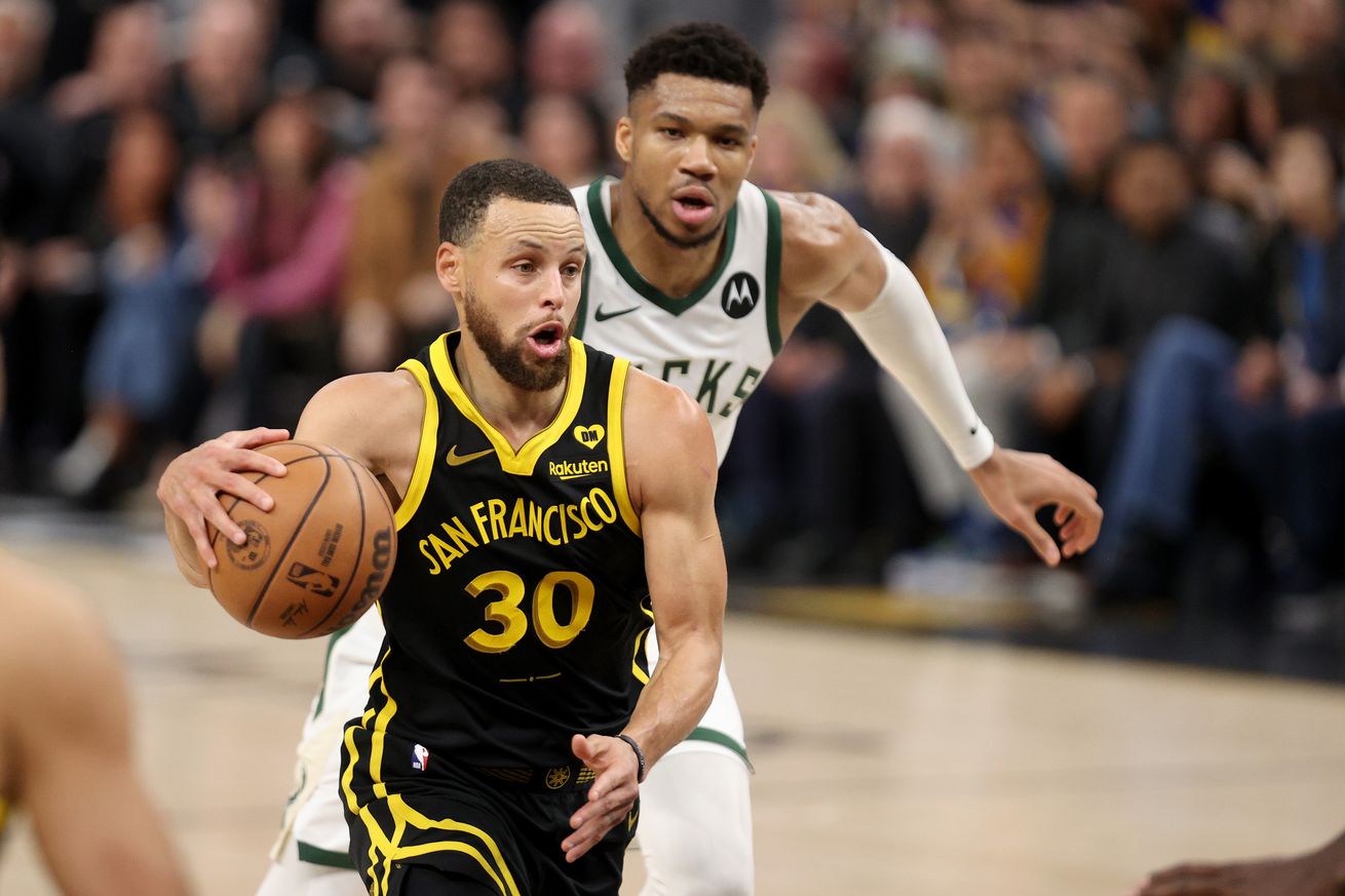 Steph Curry driving by Giannis Antetokounmpo. 