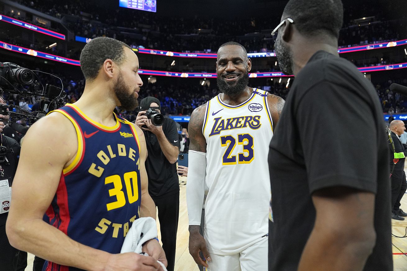 LeBron James laughing between Steph Curry and Draymond Green.