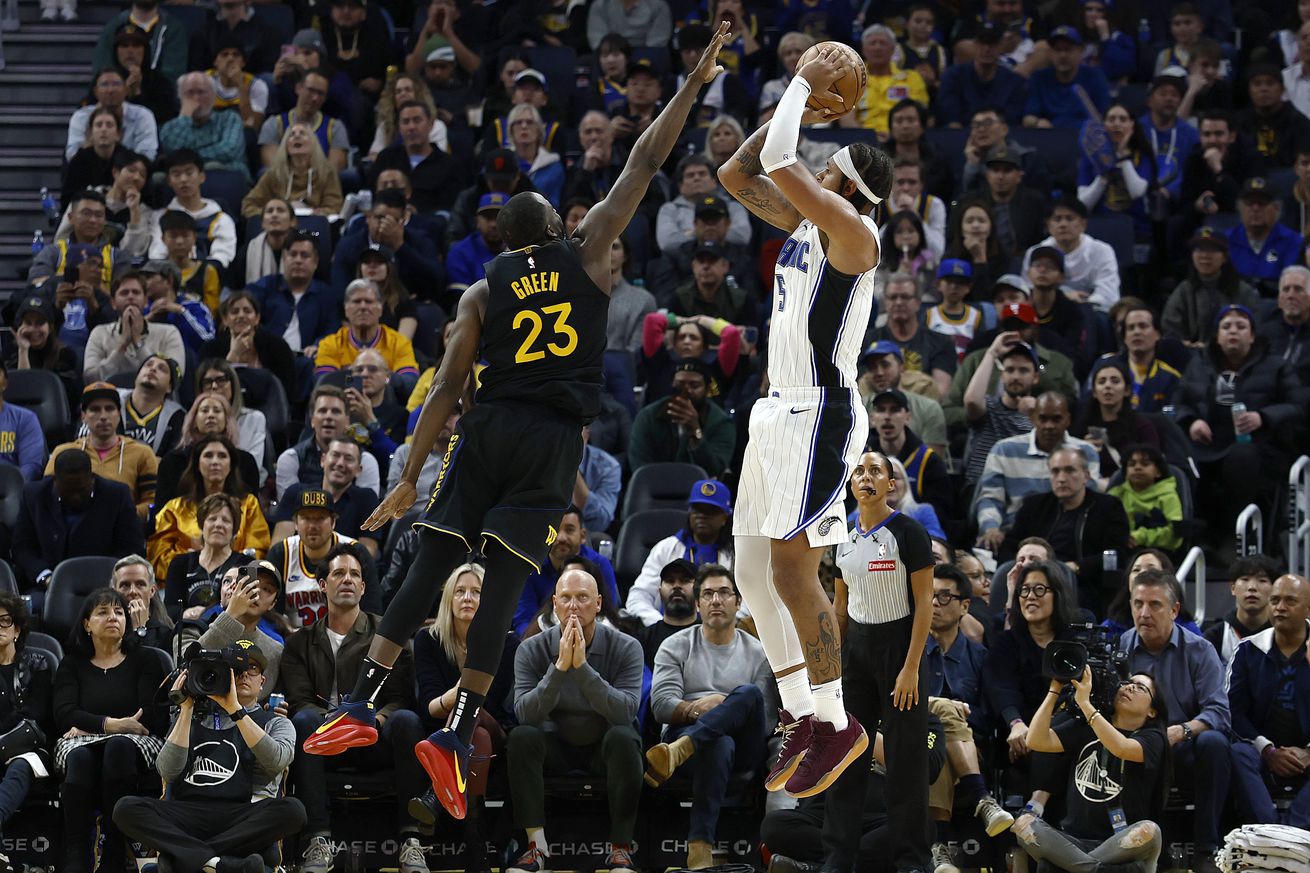 Draymond Green defending a shot attempt by Paolo Banchero. 