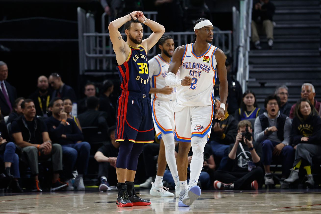 Steph Curry standing with his hands on his head next to Shai Gilgeous-Alexander. 