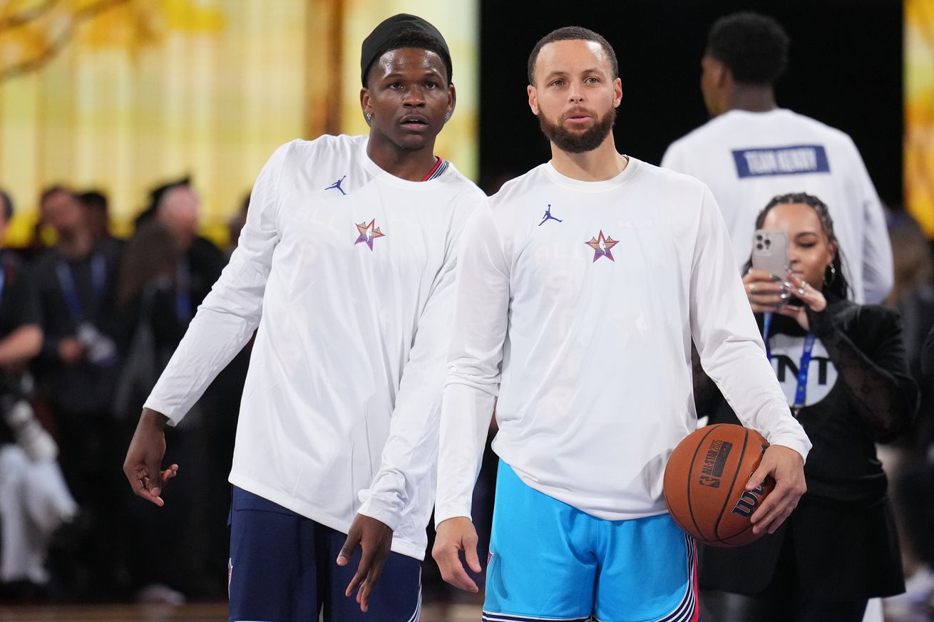 Anthony Edwards and Steph Curry, in All-Star warmups, leaning into each other to watch something. 