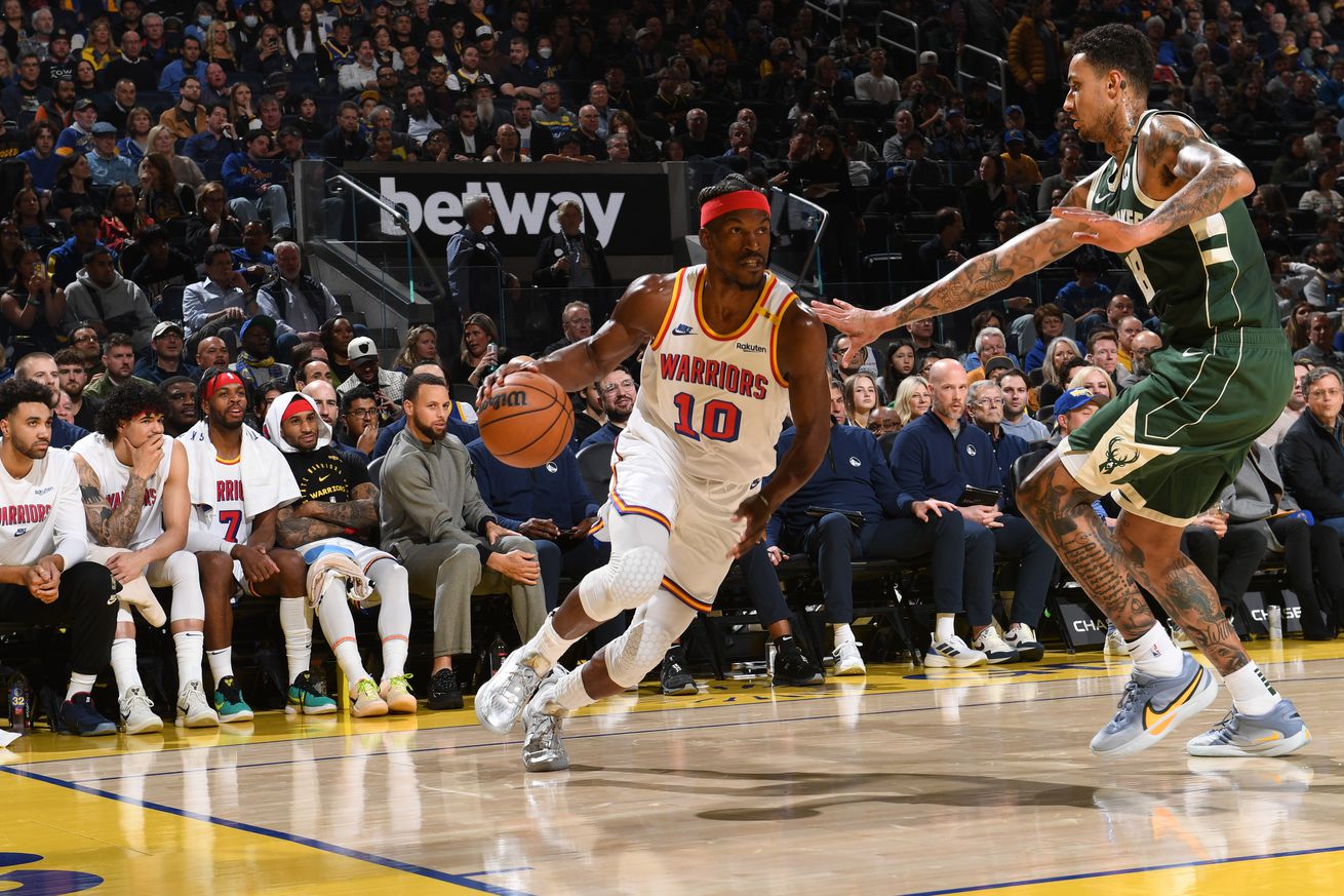 Jimmy Butler III dribbling with his right hand around a Bucks defender. 